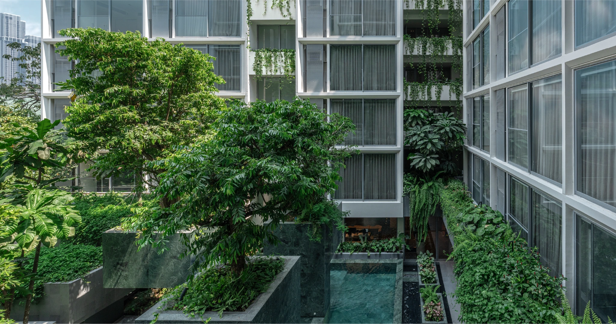 SCOPE Promsri Low Rise Condo Bangkok is nestled among lush trees and plants, creating a vibrant natural environment.