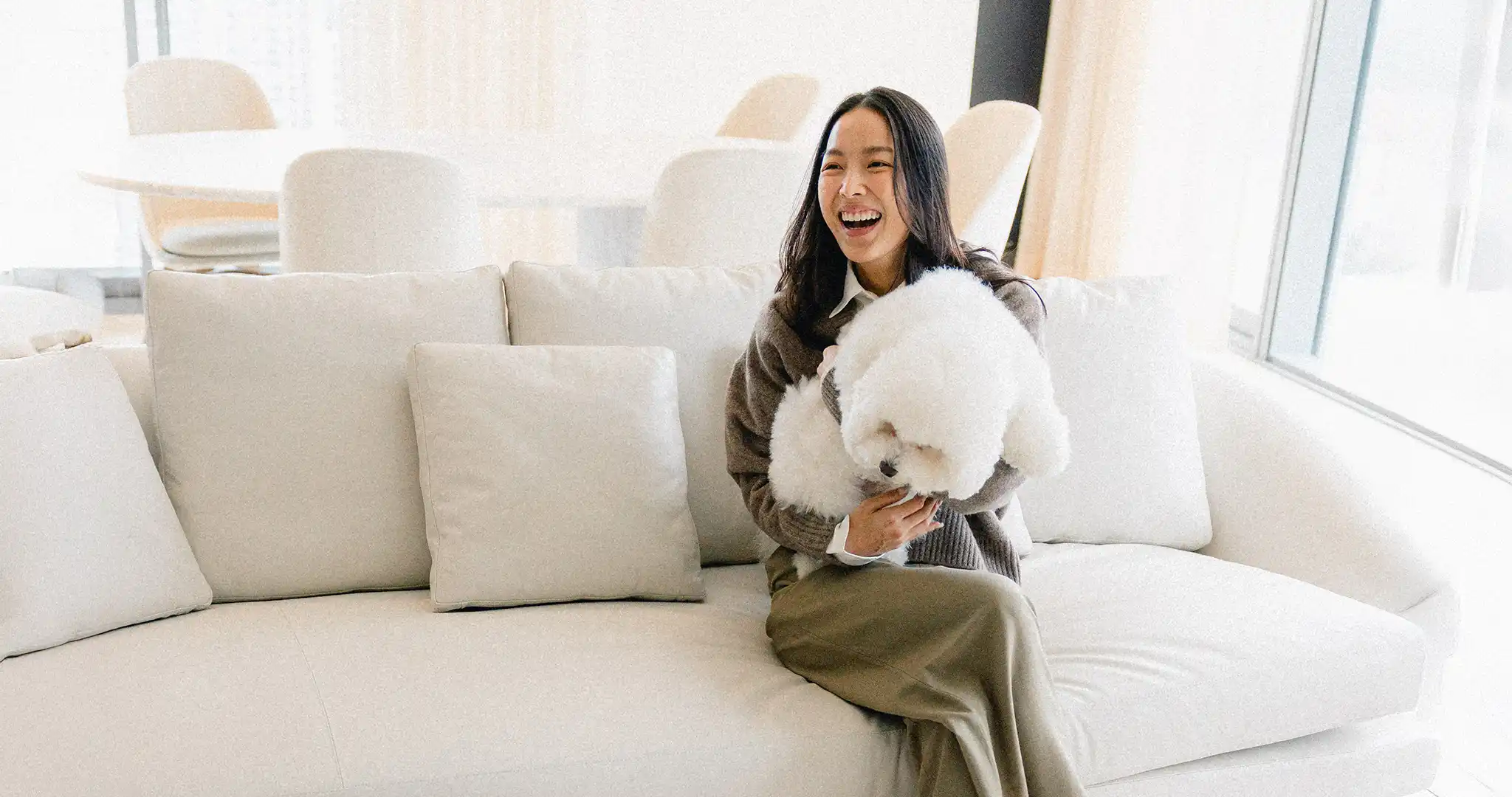 ผู้หญิงยิ้มกว้างกำลังอุ้มสุนัขสีขาวคอนโดที่เหมาะกับการลงทุนปล่อยเช่า