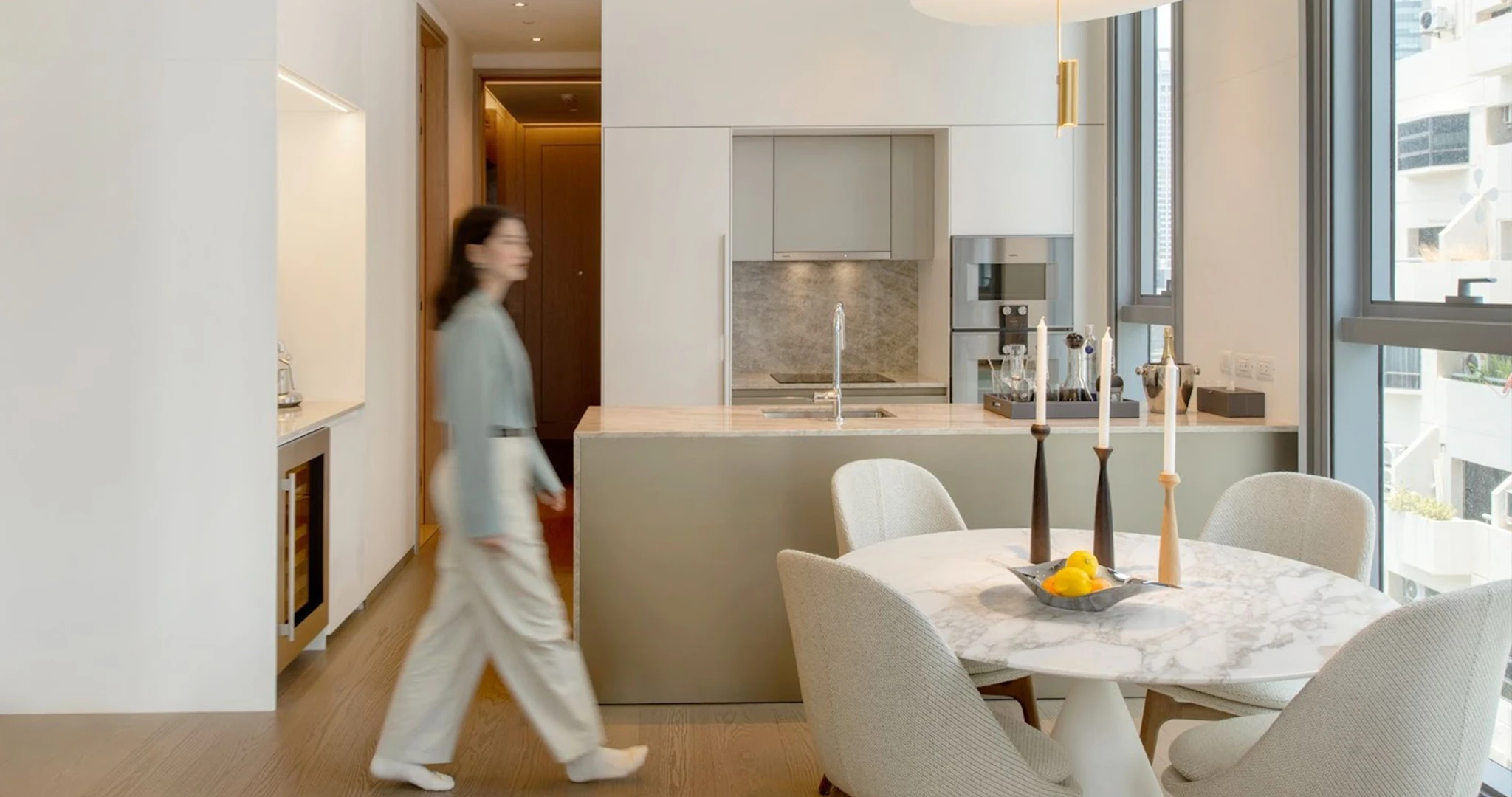 ผู้หญิงเดินในห้องนั่งเล่นคอนโดหรู SCOPE Langsuan