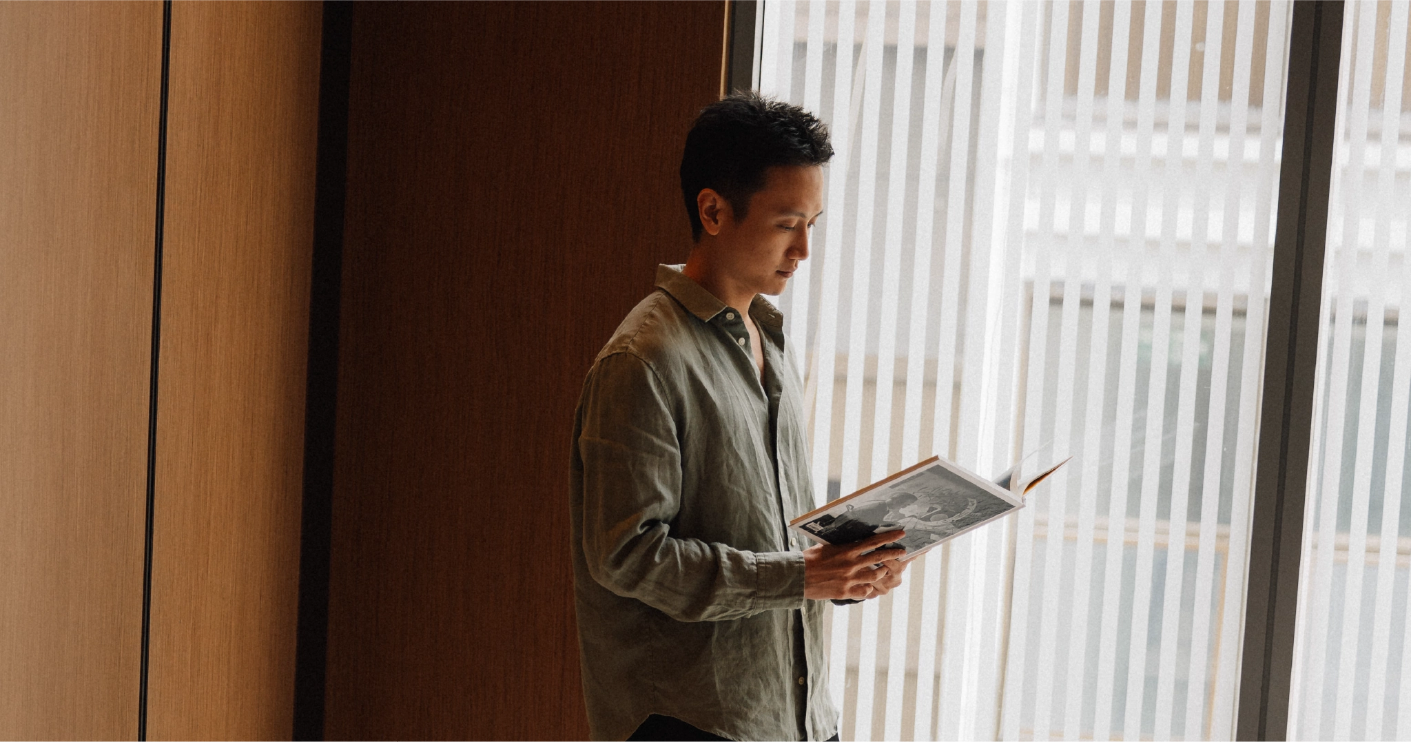 ผู้ชายยืนอ่านหนังสือเพื่อคำนวณผ่อนคอนโด